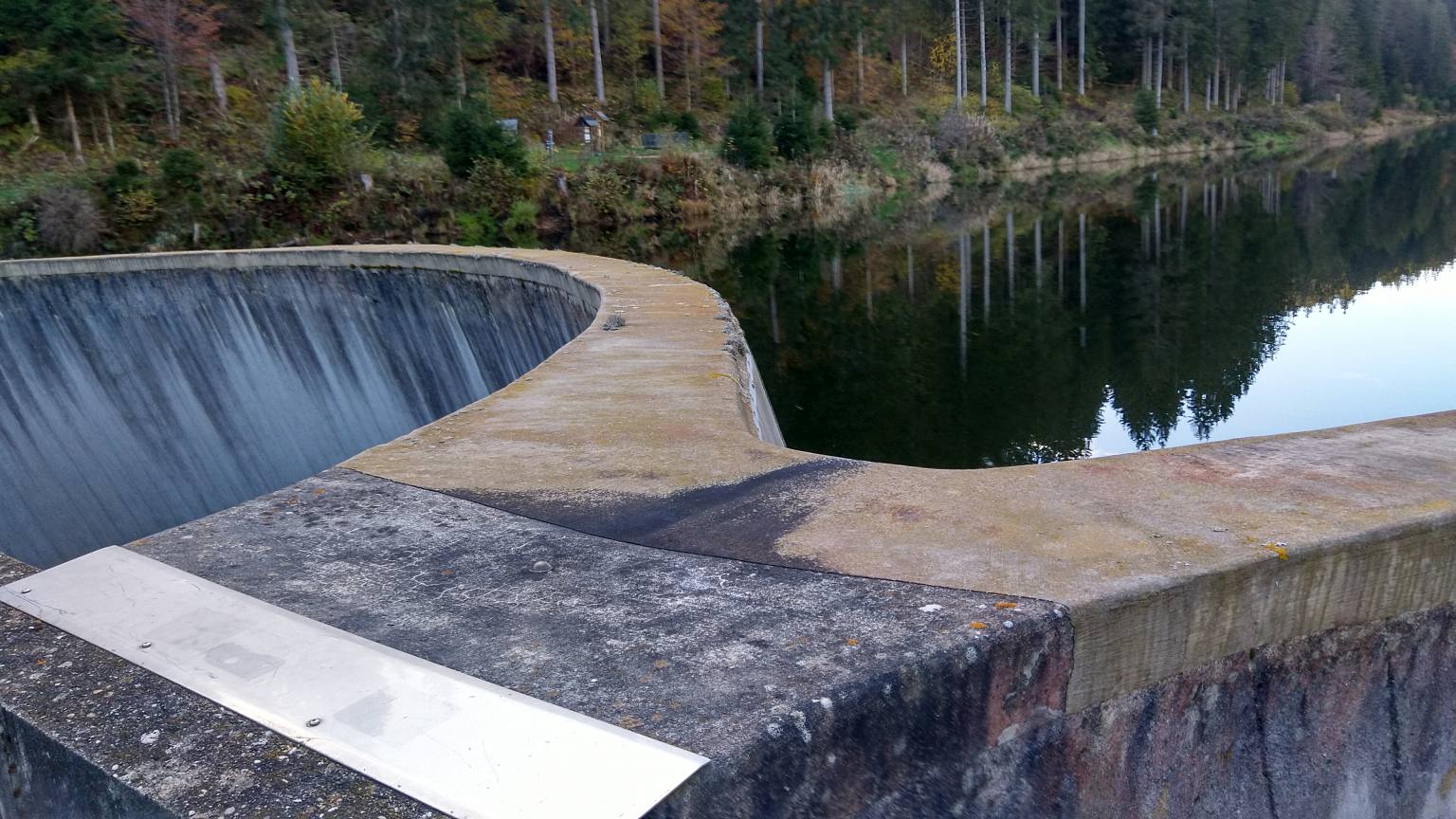 Bildtitel: Blick von der Staumauer auf den Linachstausee mit spiegelglatter Wasseroberfläche