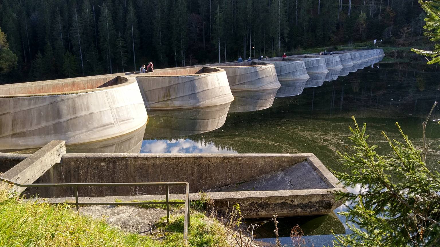 Bildtitel: Spiegelung der Staumauer des Linachstausees auf der glatten Wasseroberfläche