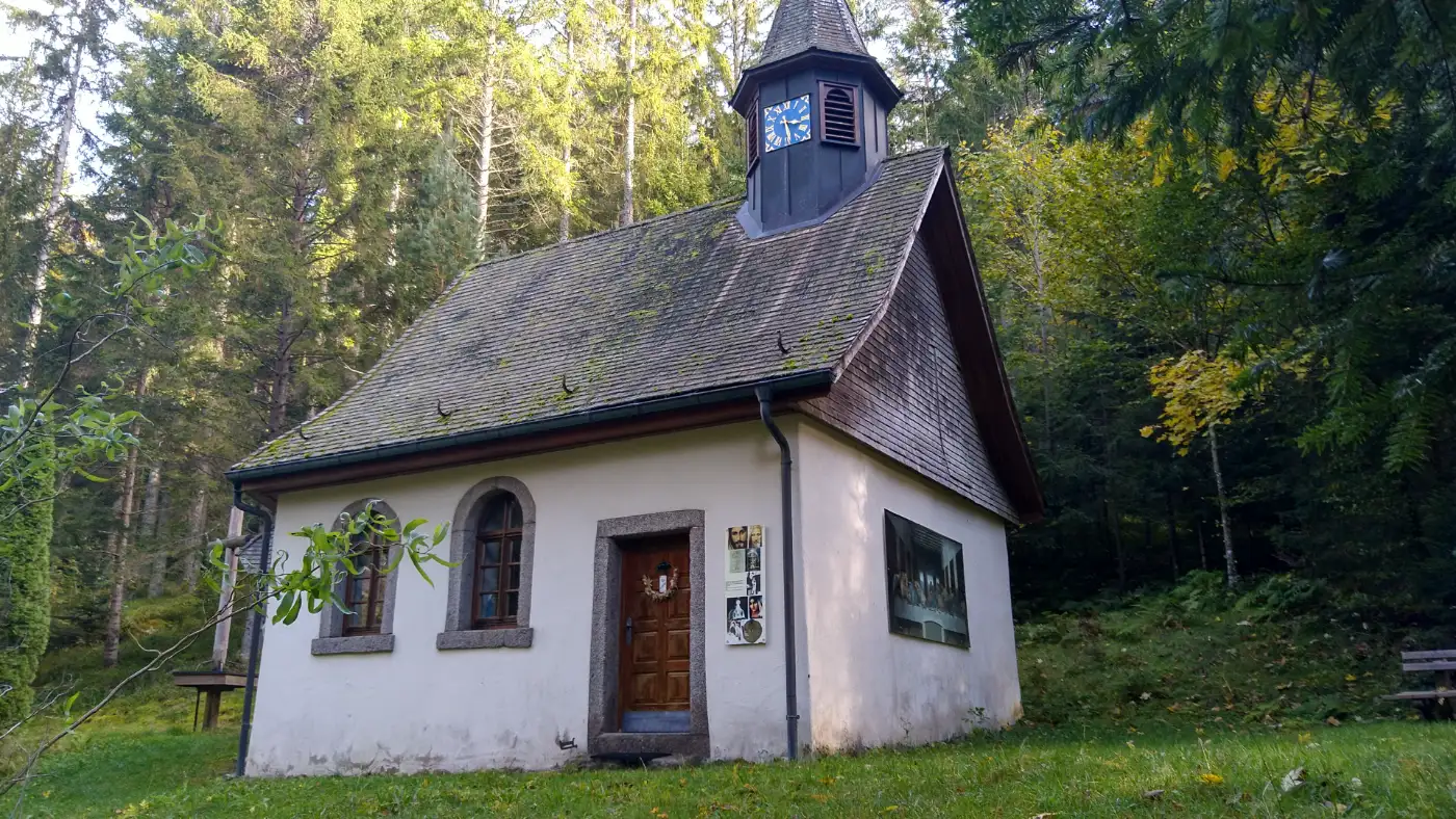 Bildtitel: Laubwaldkapelle mit Holzschindeldach, umgeben von Tannenwald