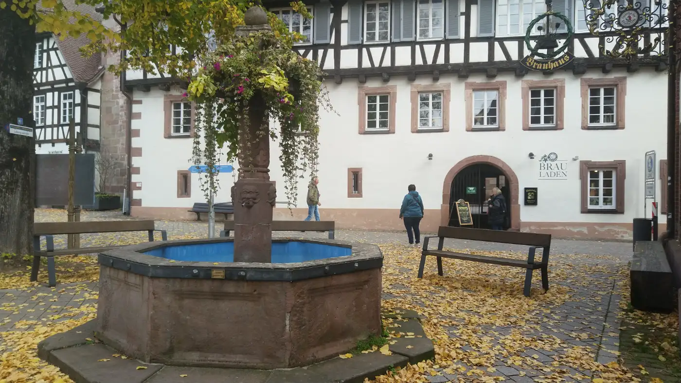 Bildtitel: Lindenbrunnen in Alpirsbach mit Brauladen im Hintergrund
